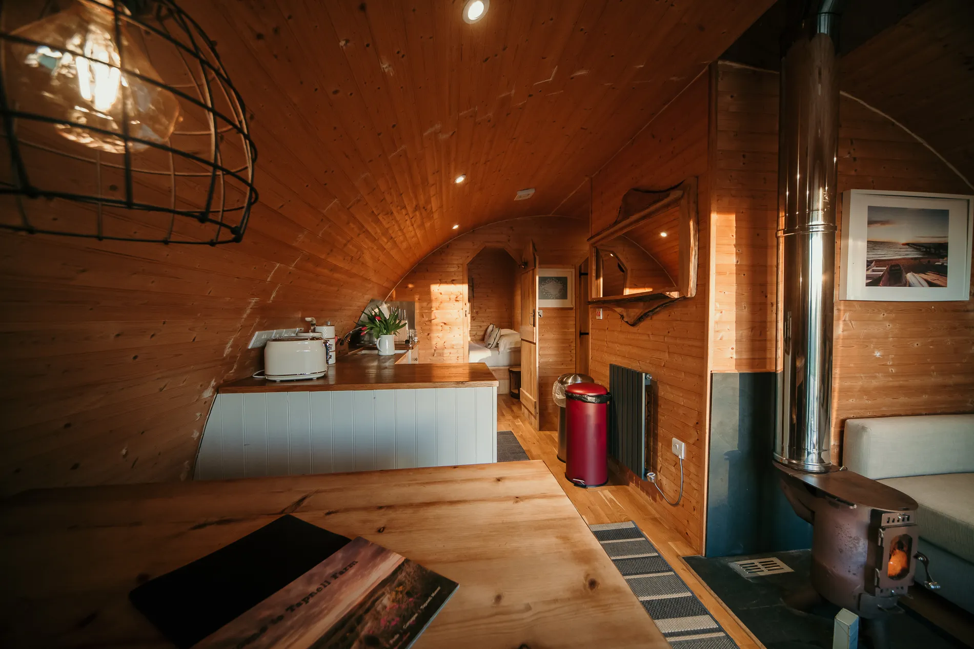 Cosy wooden cabin interior with kitchenette, wood-burning stove and arched ceiling
