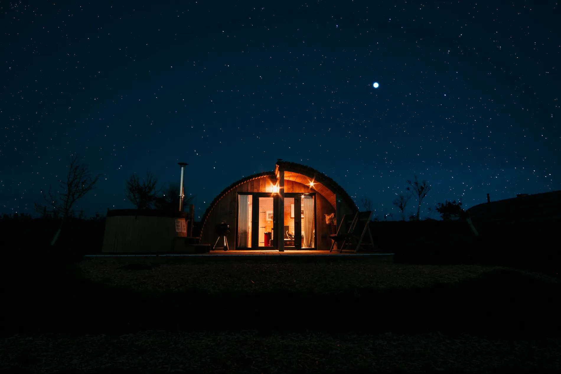 Cosy, warmly lit cabin under a starry night sky