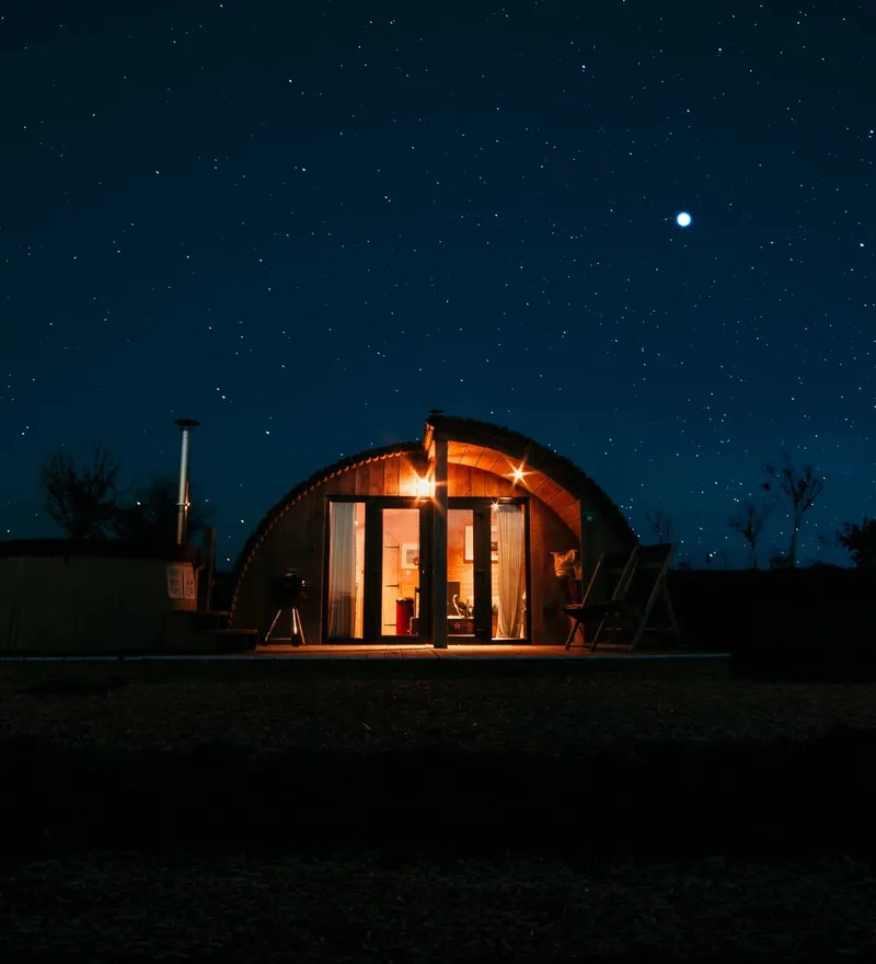Cosy, warmly lit cabin under a starry night sky