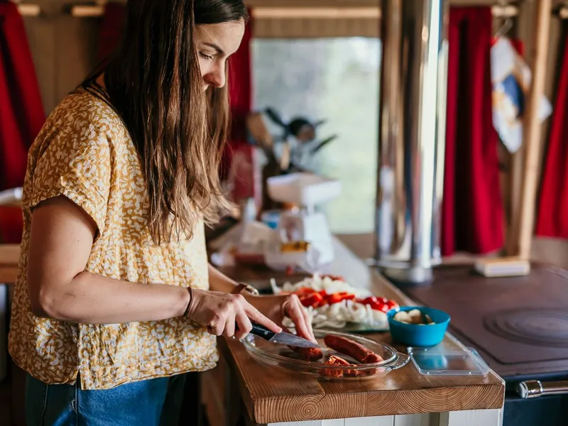 Woman preparing food at a wooden counter inside a safari tent kitchen