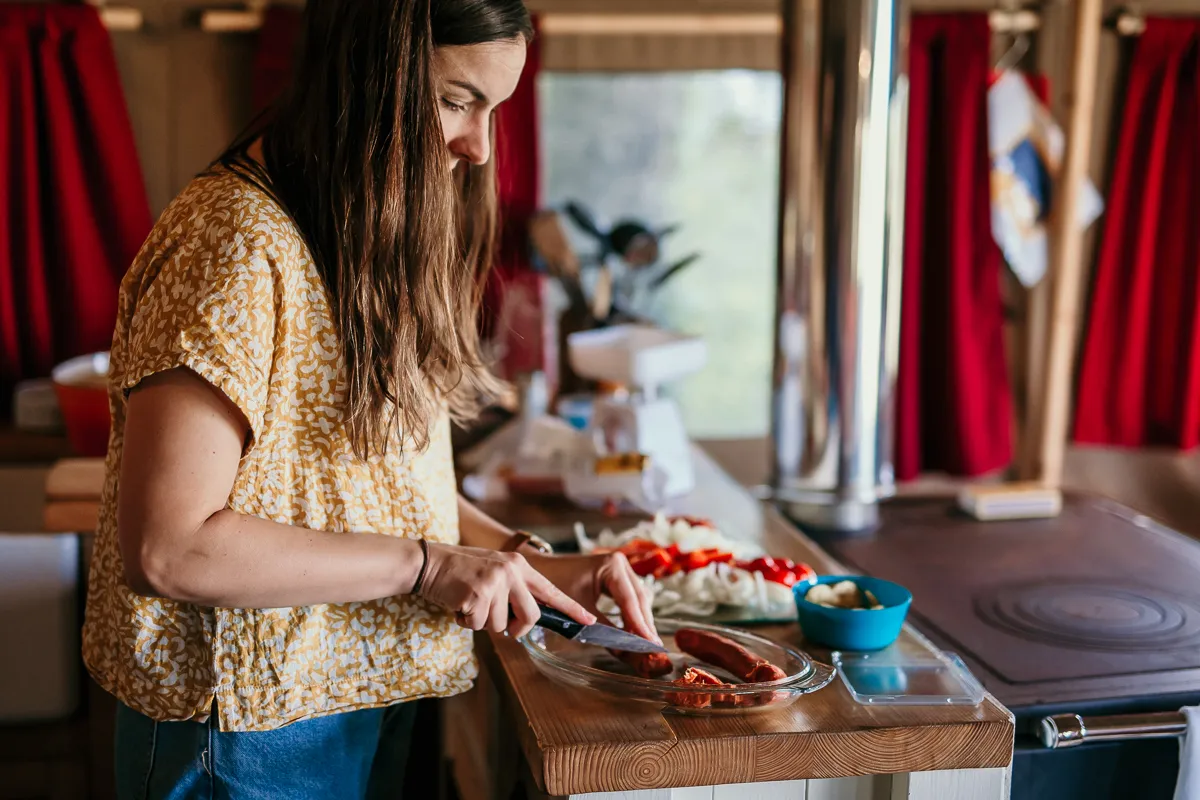 Woman preparing food at a wooden counter inside a safari tent kitchen