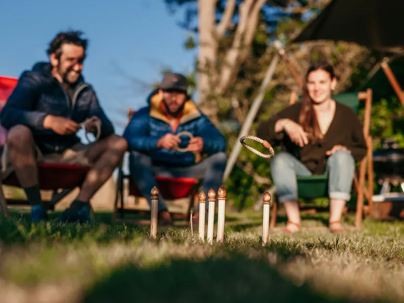 Friends playing ring toss by a safari tent at a campsite