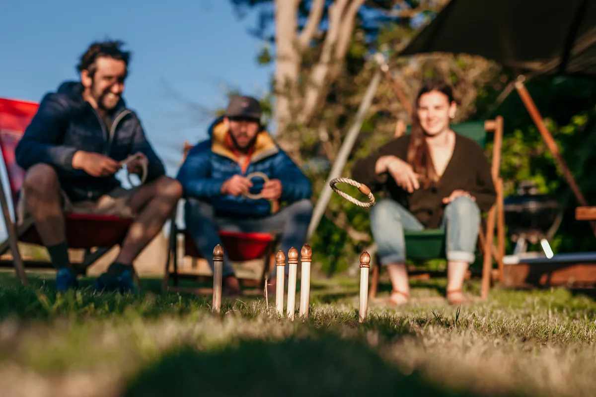 Friends playing ring toss by a safari tent at a campsite
