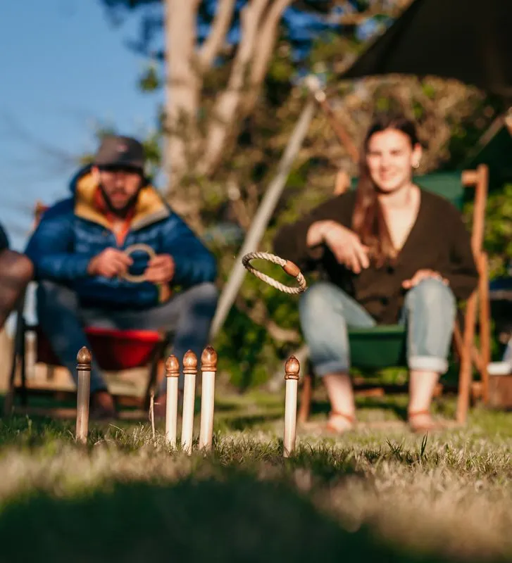 Friends playing ring toss by a safari tent at a campsite