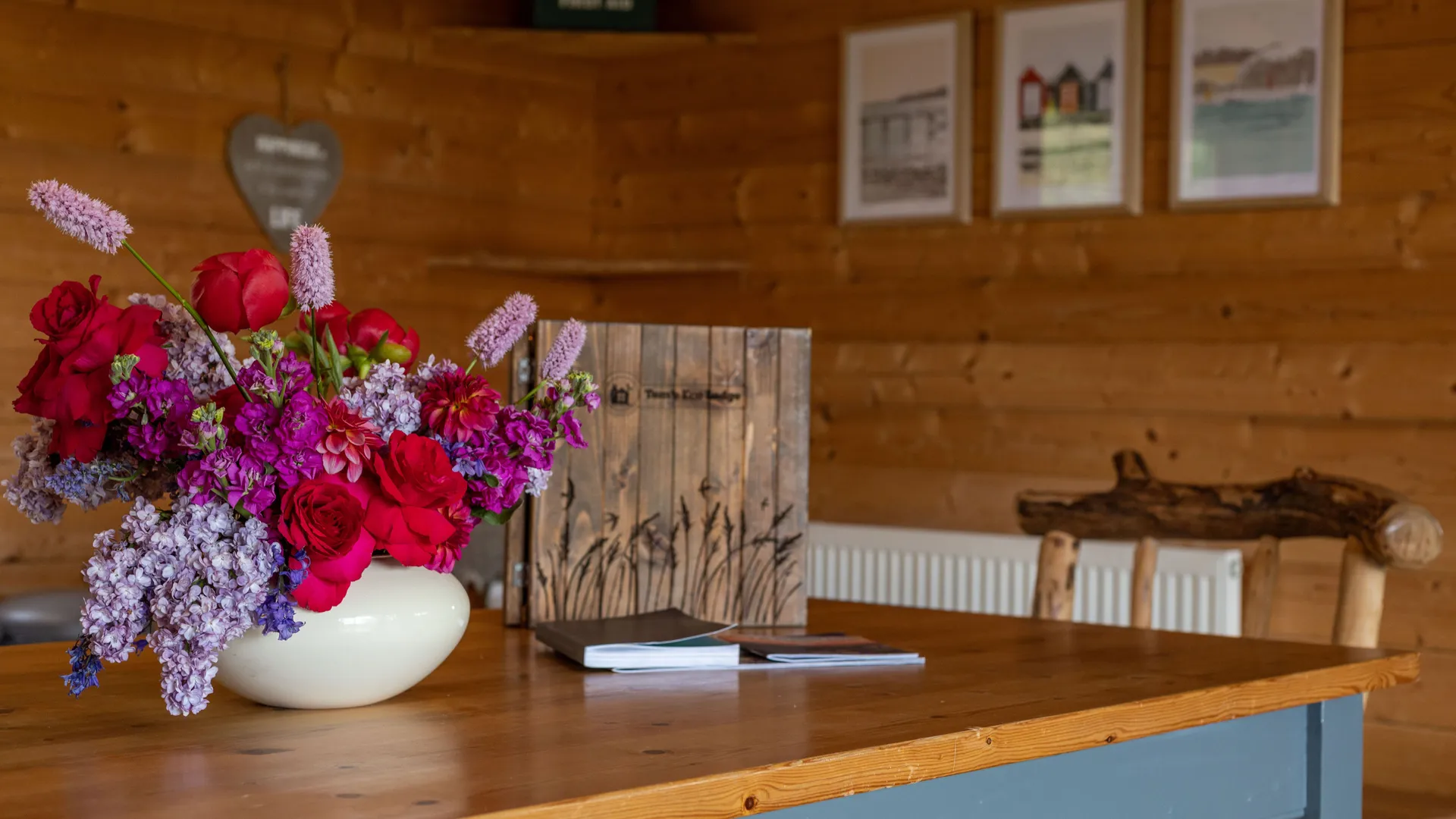 Bouquet of bright flowers in a white vase on a wooden table inside a cosy cabin