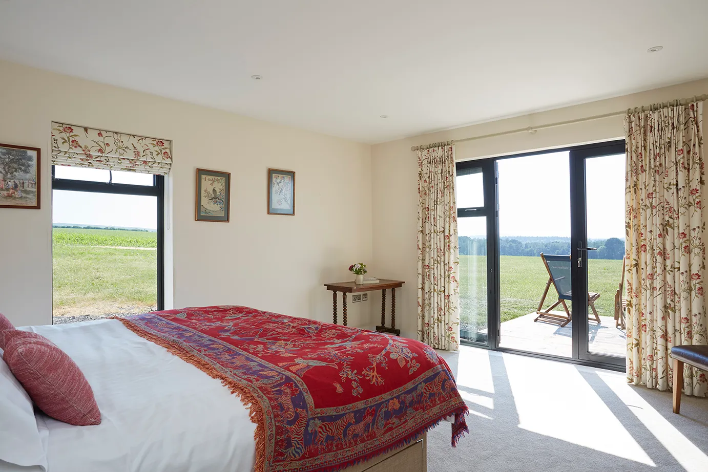 Double bedroom with floral curtains, patio doors and countryside views at Wendy House near Tapnell Farm