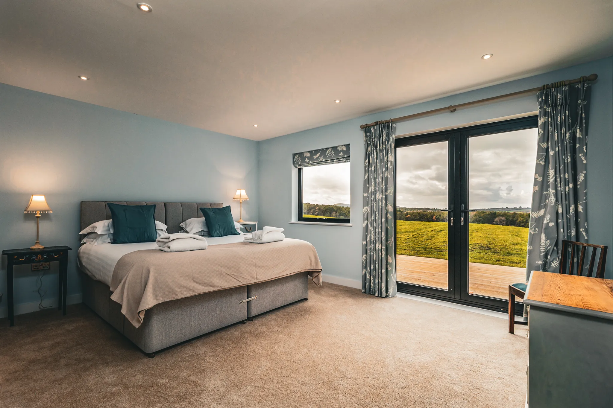 Cosy bedroom with double bed, bedside lamps and French doors opening onto countryside views