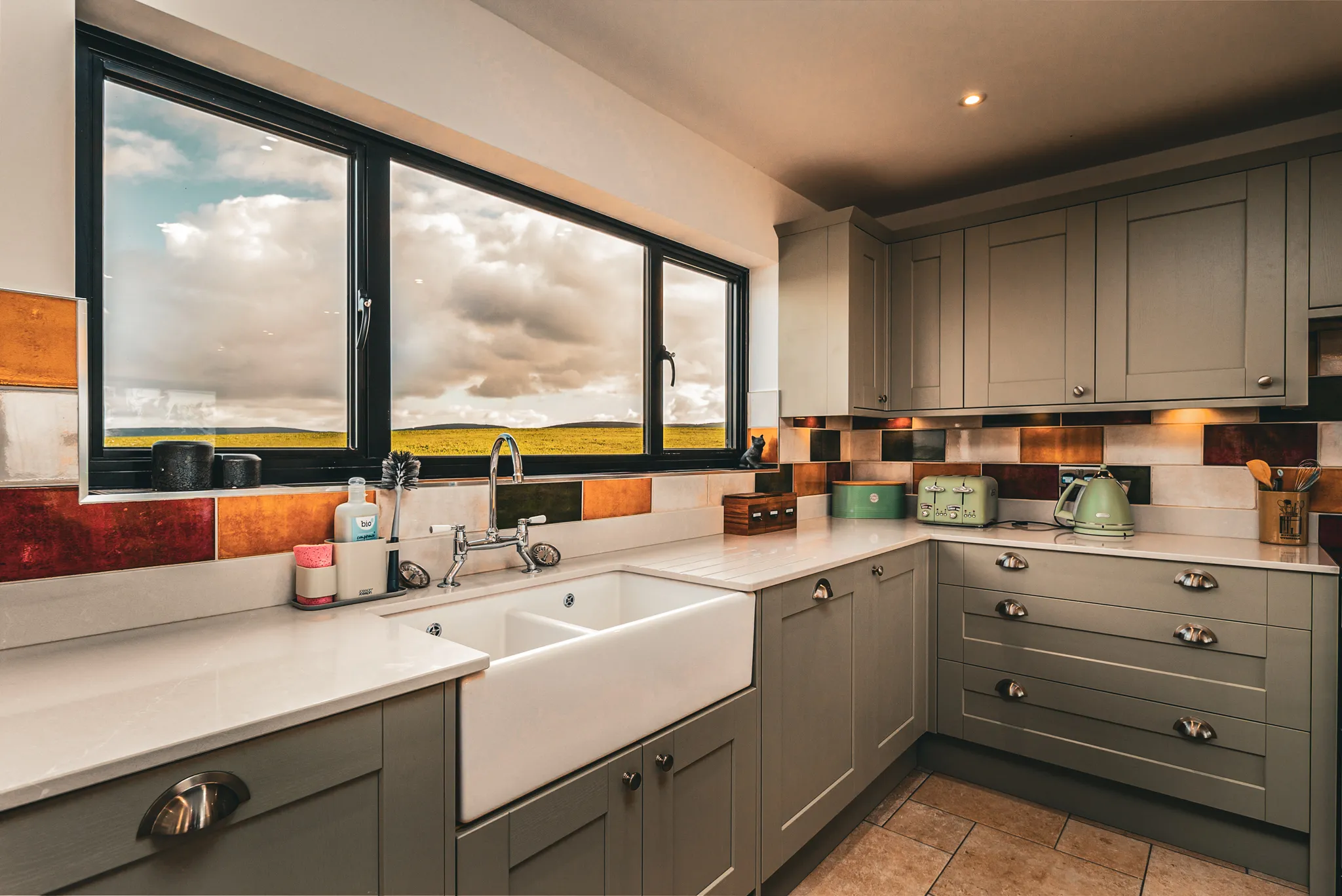 Cosy modern kitchen with farmhouse sink and large window overlooking countryside