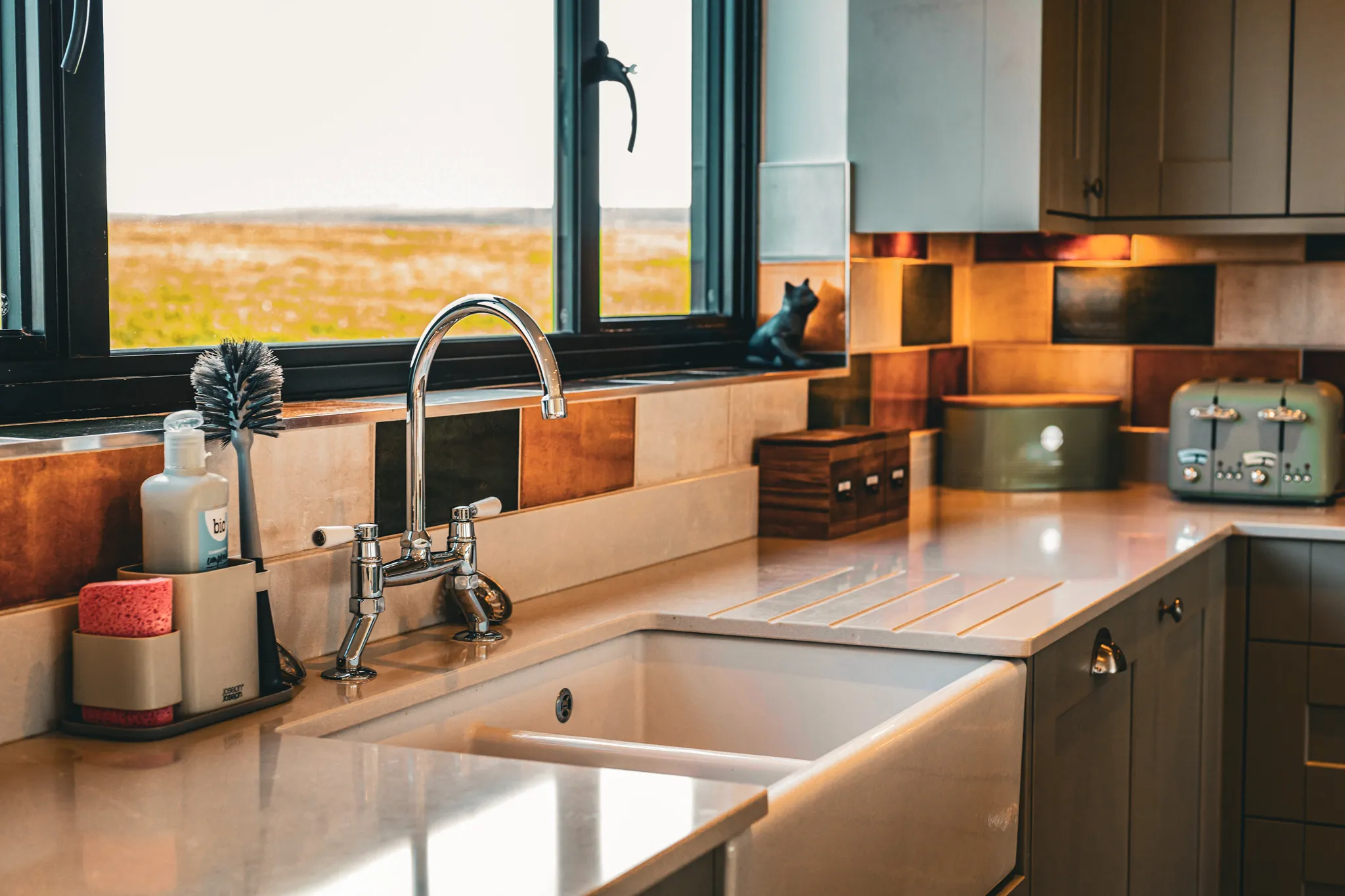 Cosy kitchen sink with chrome tap, tiled splashback and window view over the countryside