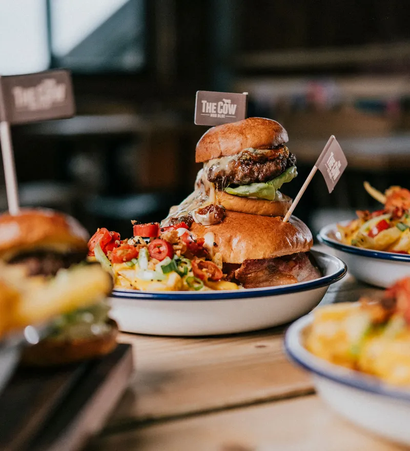 Gourmet cheeseburger with melted cheese and salad in a brioche bun, served with loaded chips at The Cow restaurant