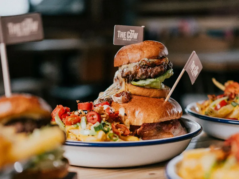 Gourmet cheeseburger with melted cheese and salad in a brioche bun, served with loaded chips at The Cow restaurant