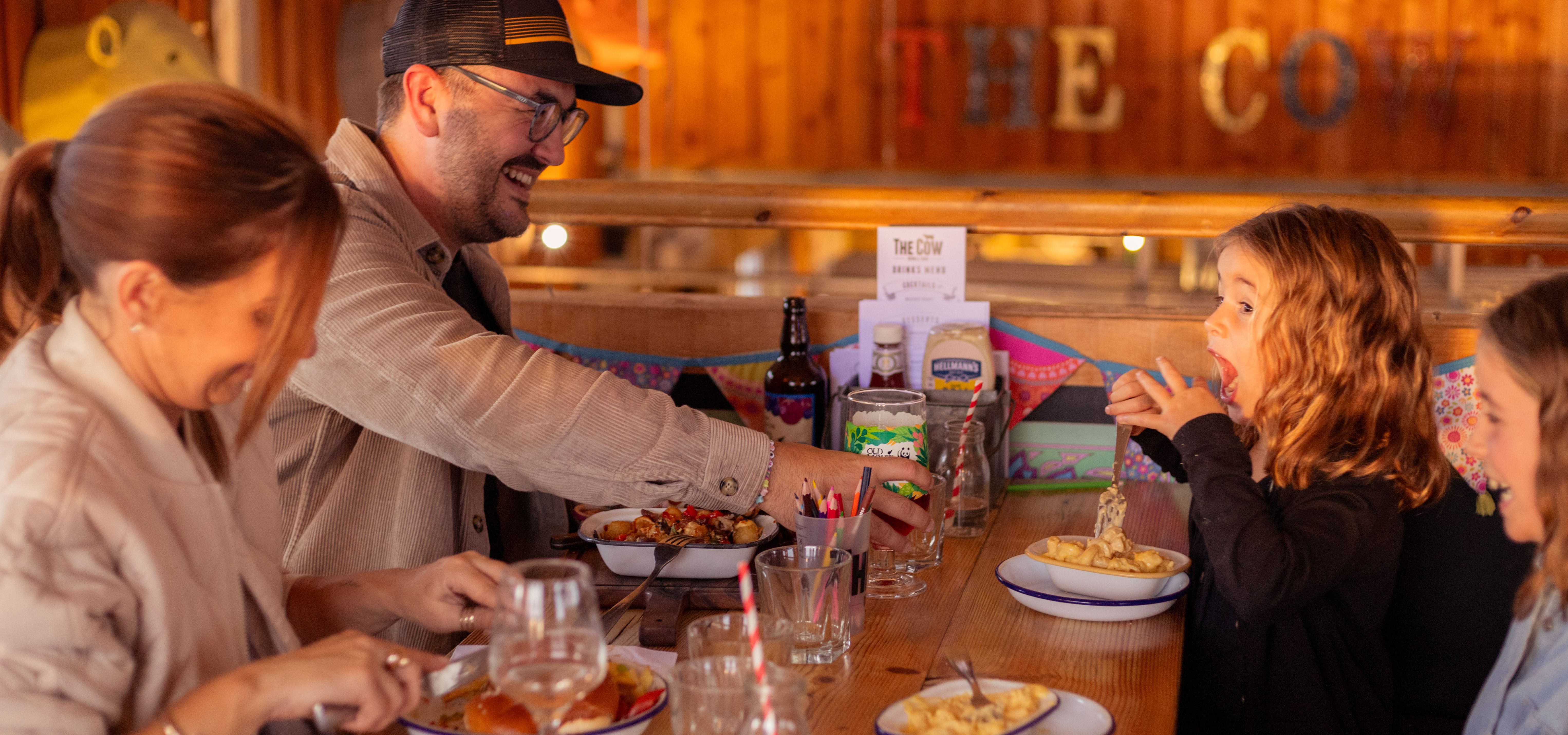Family enjoying a meal together at a wooden table in a rustic farm-style restaurant