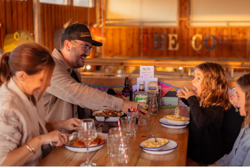 Family enjoying a meal together at a wooden table in a rustic farm-style restaurant