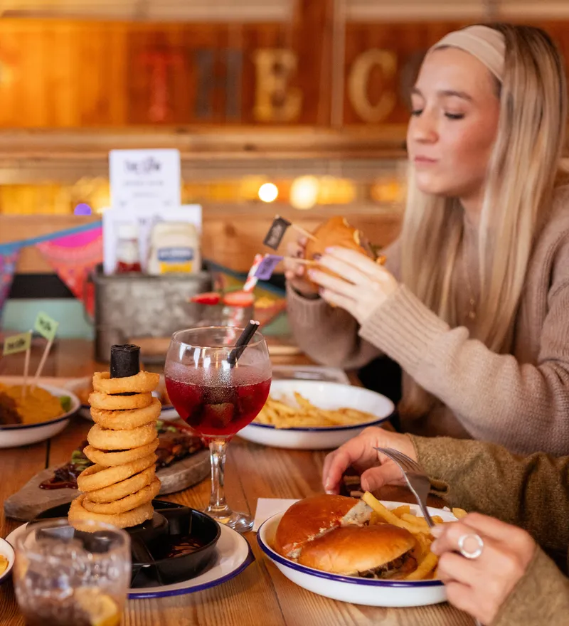 Friends enjoying burgers, chips and onion rings at a rustic farm café table
