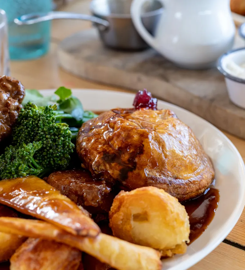 Sunday roast with Yorkshire pudding, roast potatoes, carrots, broccoli and gravy, served with a pint of lager