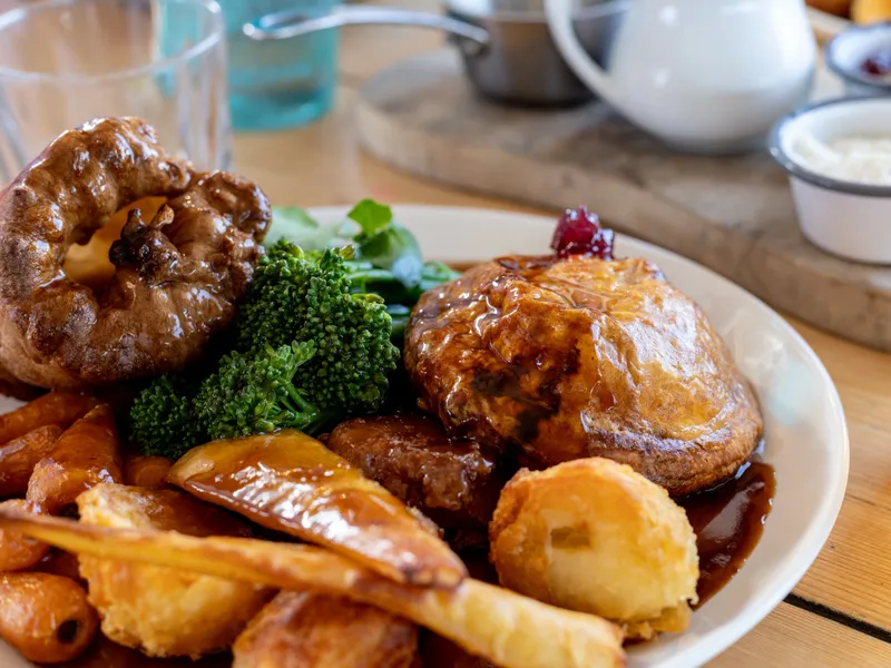 Sunday roast with Yorkshire pudding, roast potatoes, carrots, broccoli and gravy, served with a pint of lager