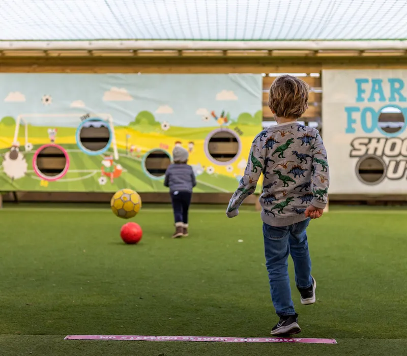 Children playing football shoot-out game at a farm park outdoor play area