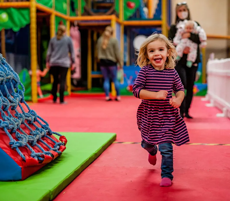 Young girl running and smiling in the soft play barn at Tapnell Farm Park
