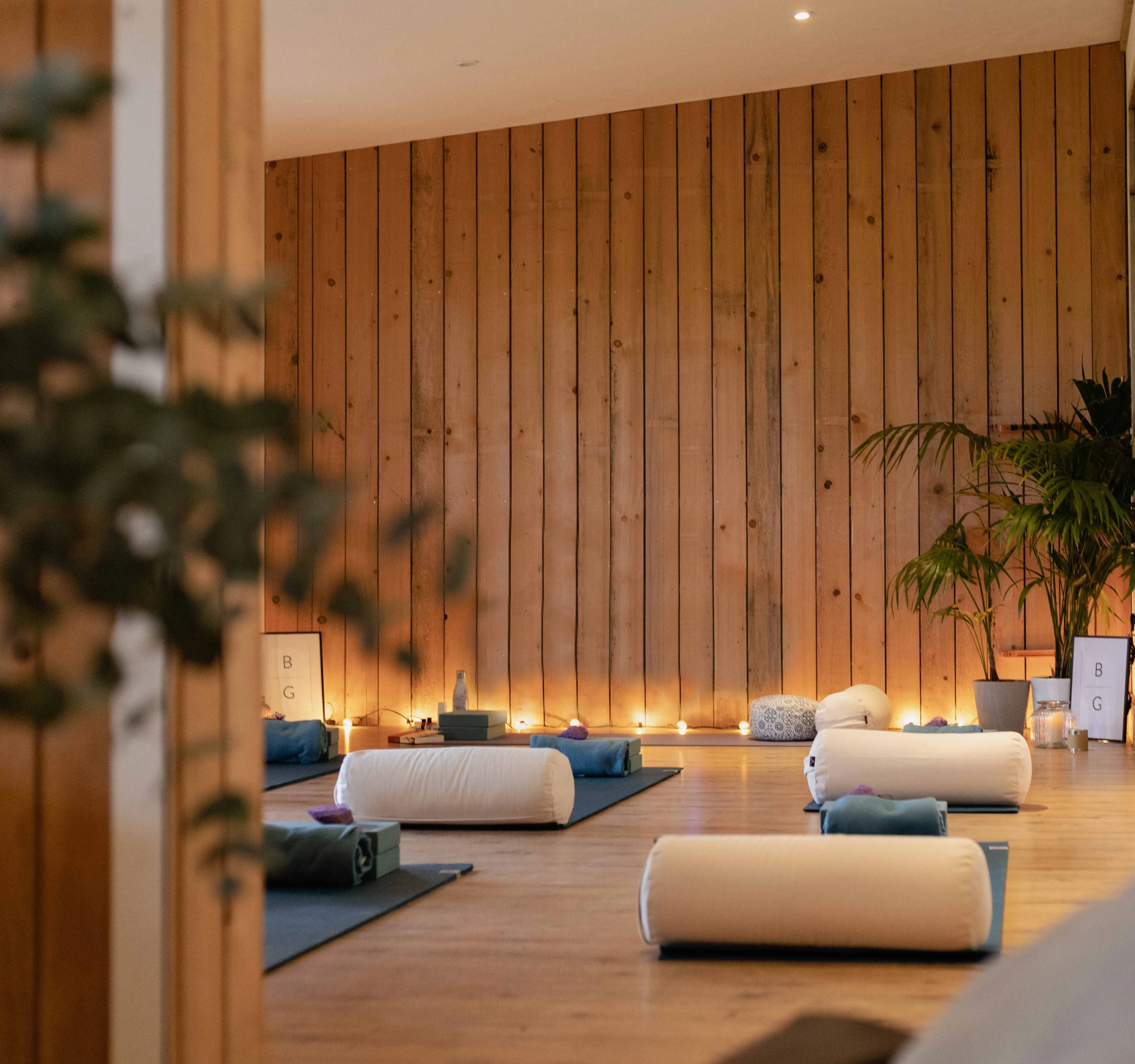 Cosy yoga studio with mats, bolsters and warm candlelight against a wooden wall