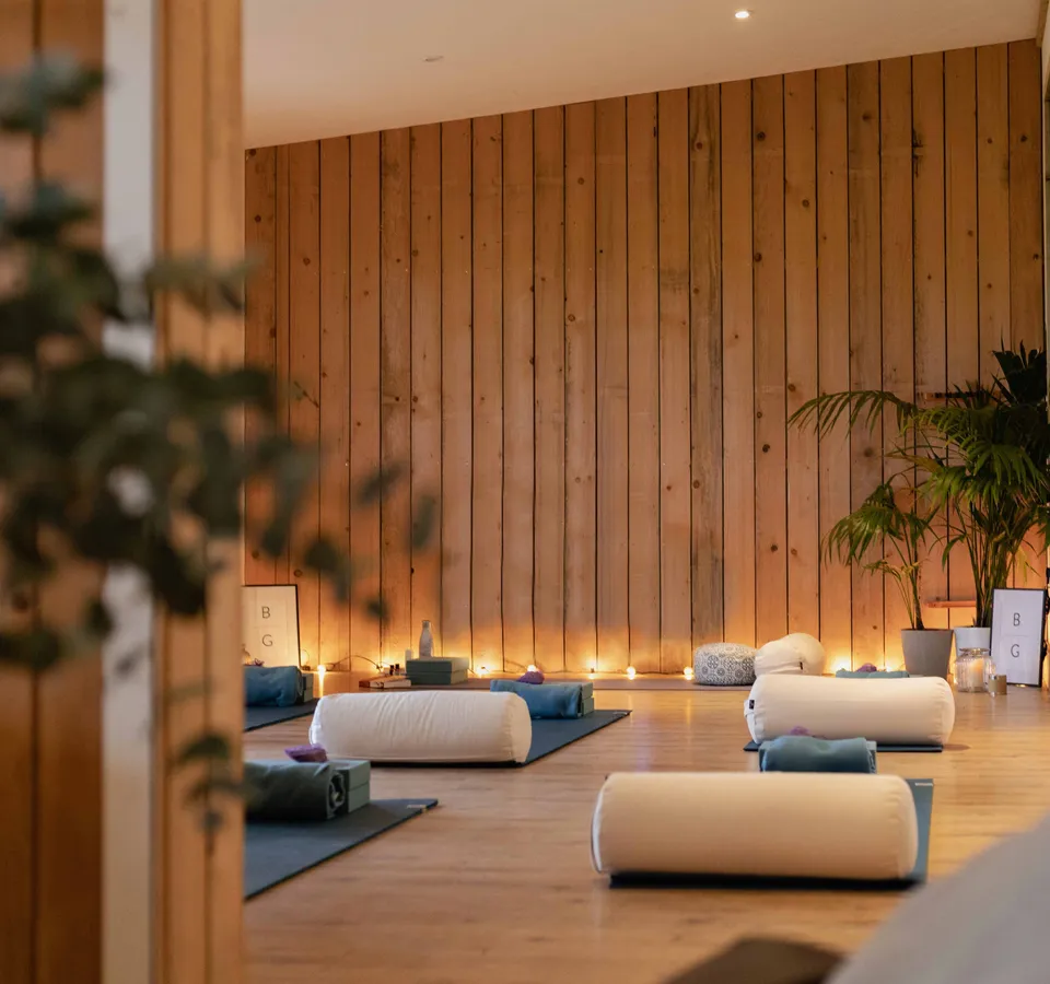 Cosy yoga studio with mats, bolsters and warm candlelight against a wooden wall