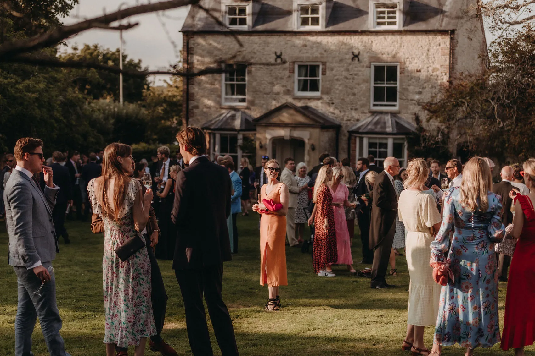 Guests socialising on a lawn outside a large stone country house