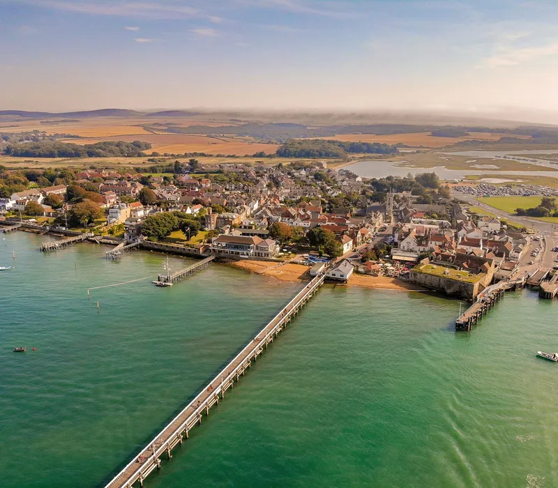 Aerial view of a coastal town with a long pier and turquoise sea