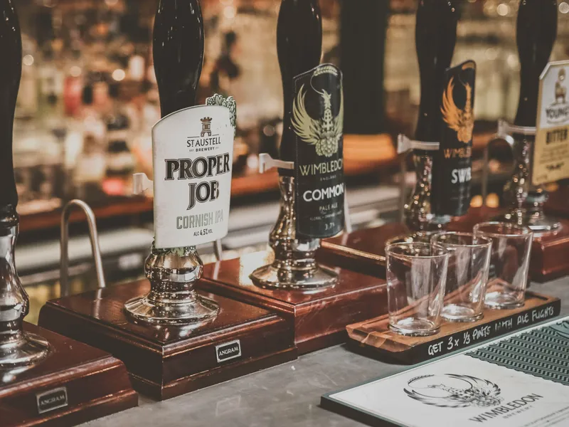 Beer pumps on a pub bar with pint glasses and tasting tray