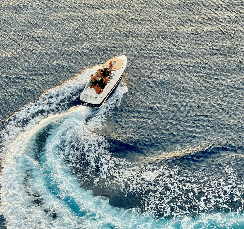 Aerial view of a speedboat turning on the sea, leaving a foamy wake behind it