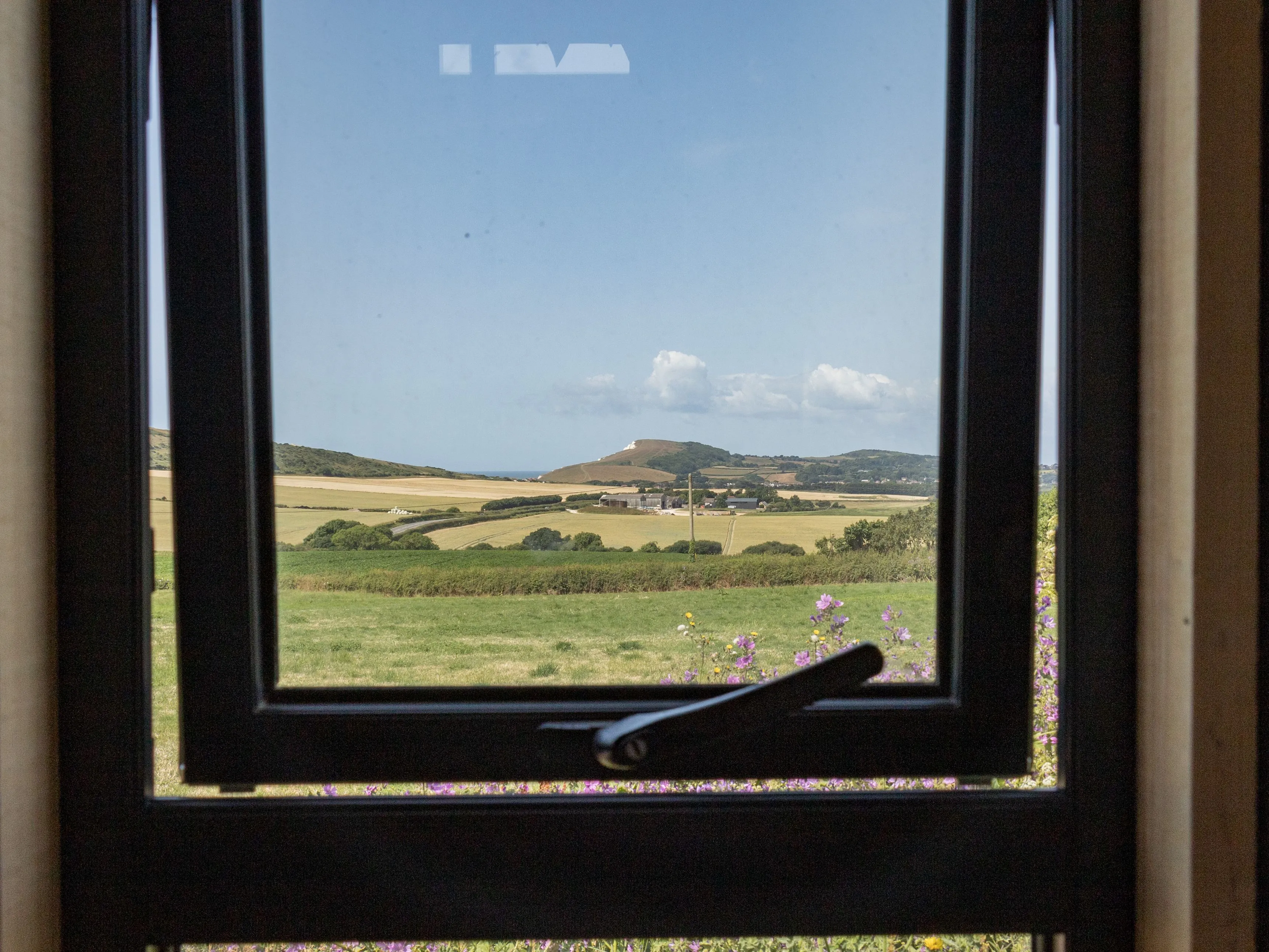 Countryside and sea view through a window at Camp Tapnell container accommodation