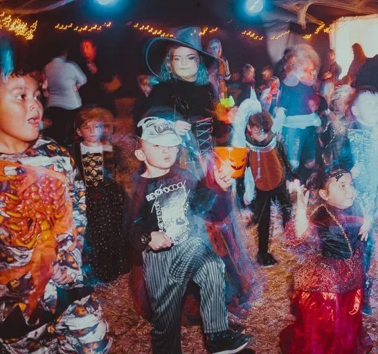 Children in Halloween costumes dancing at a party with colourful lights and motion blur