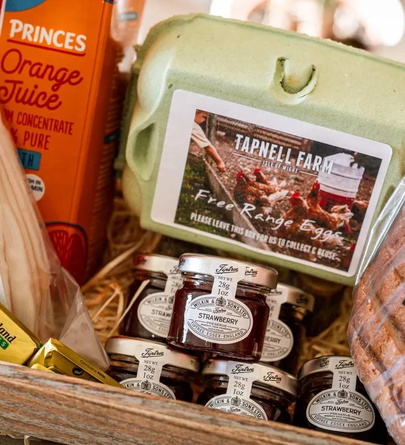 Breakfast hamper with free-range eggs, orange juice, bacon, butter and small jars of strawberry jam