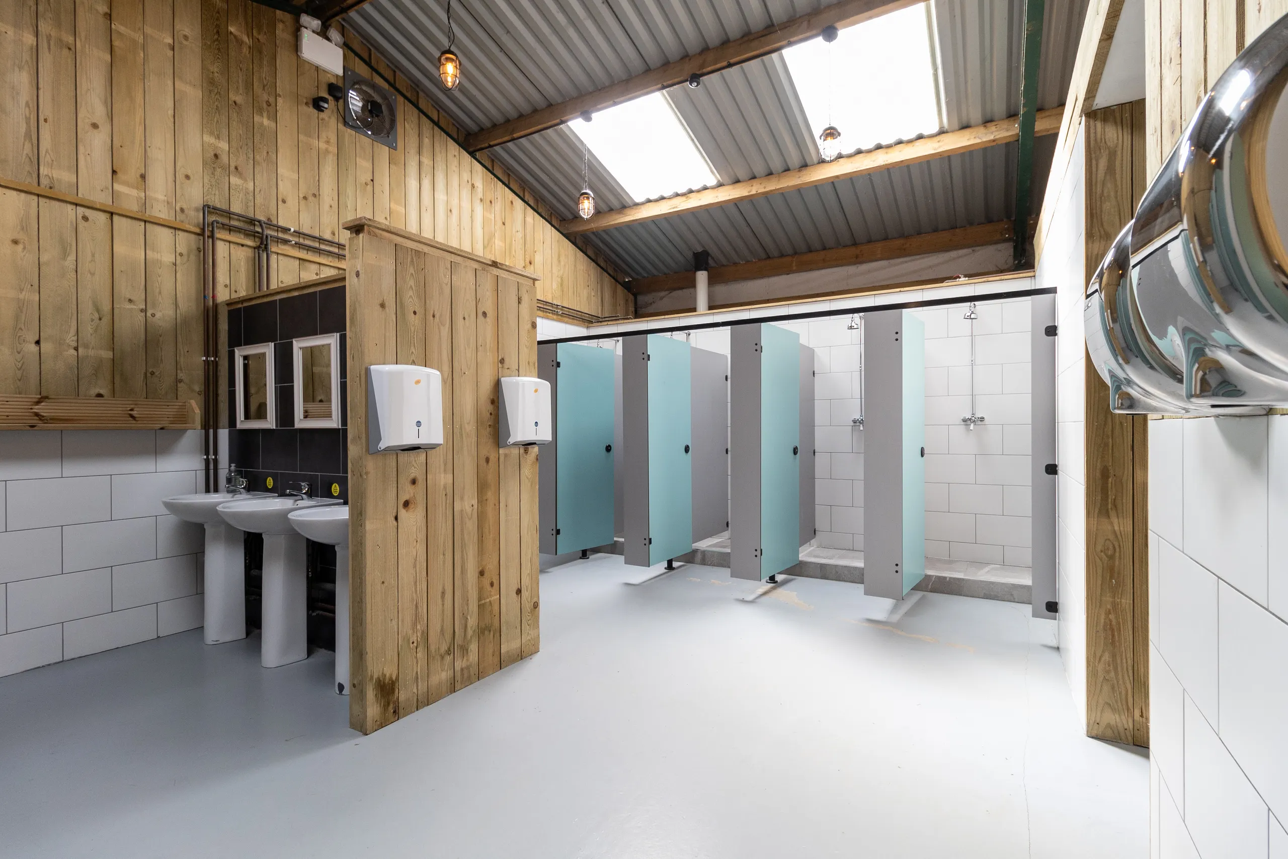 Modern campsite washroom with sinks, hand dryers and shower cubicles in a timber-clad building