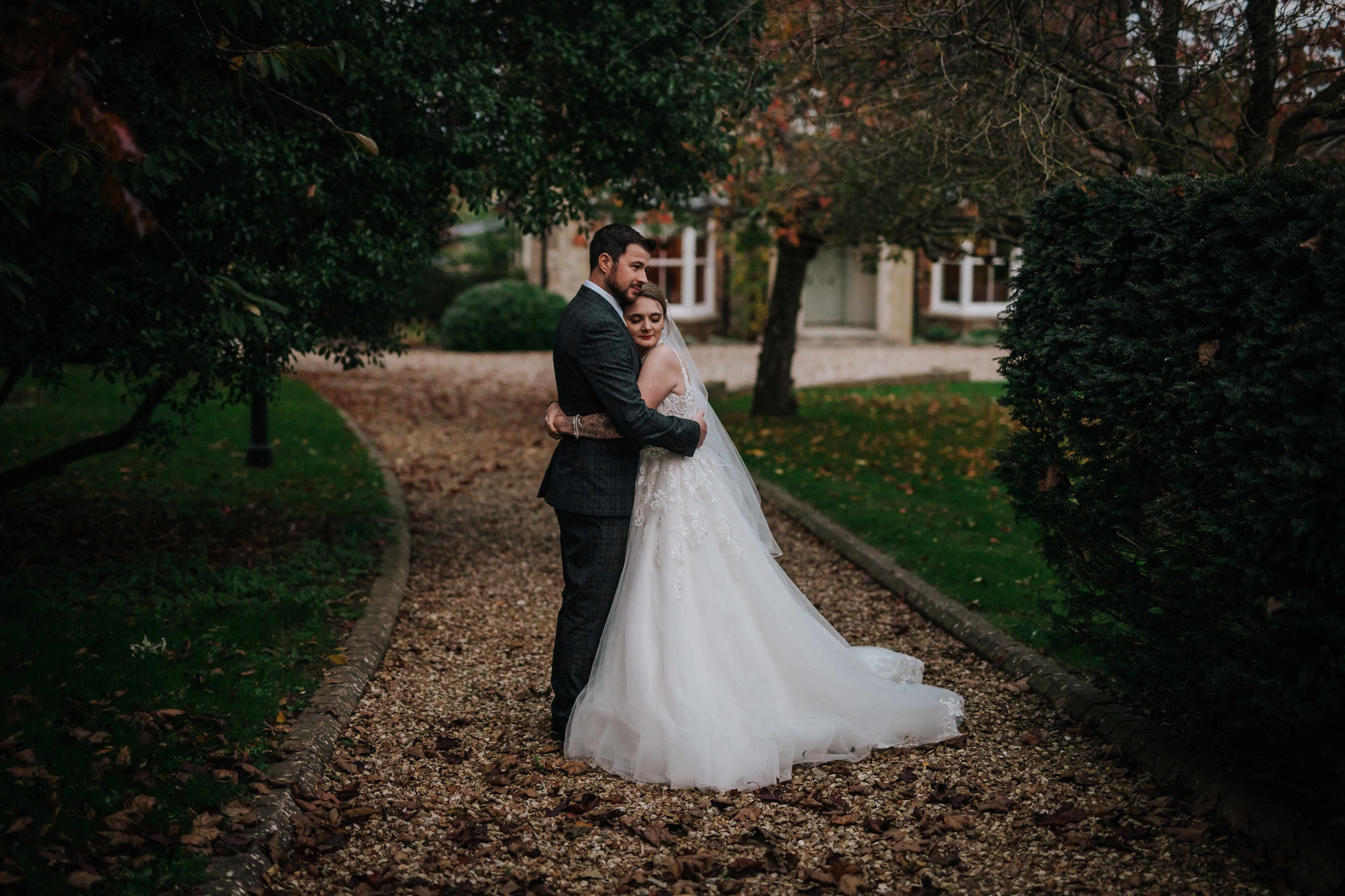 Bride and groom embracing on a gravel path in a garden