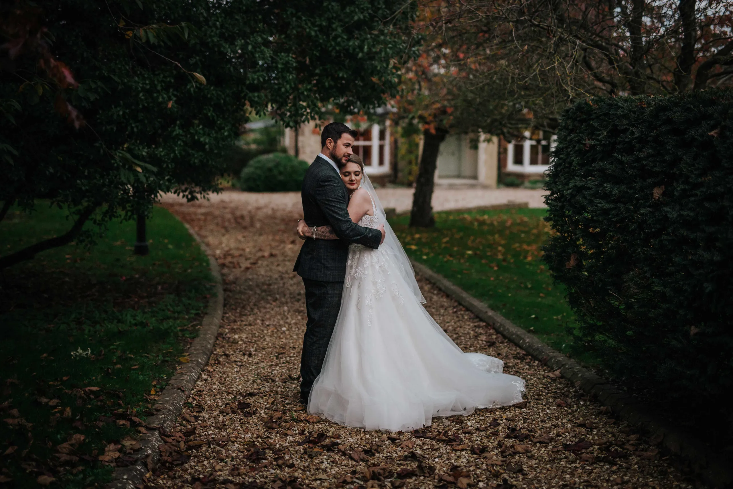 Bride and groom embracing on a gravel path in a garden