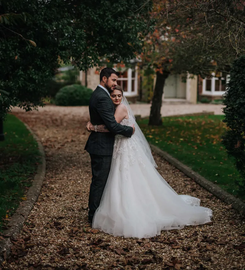Bride and groom embracing on a gravel path in a garden