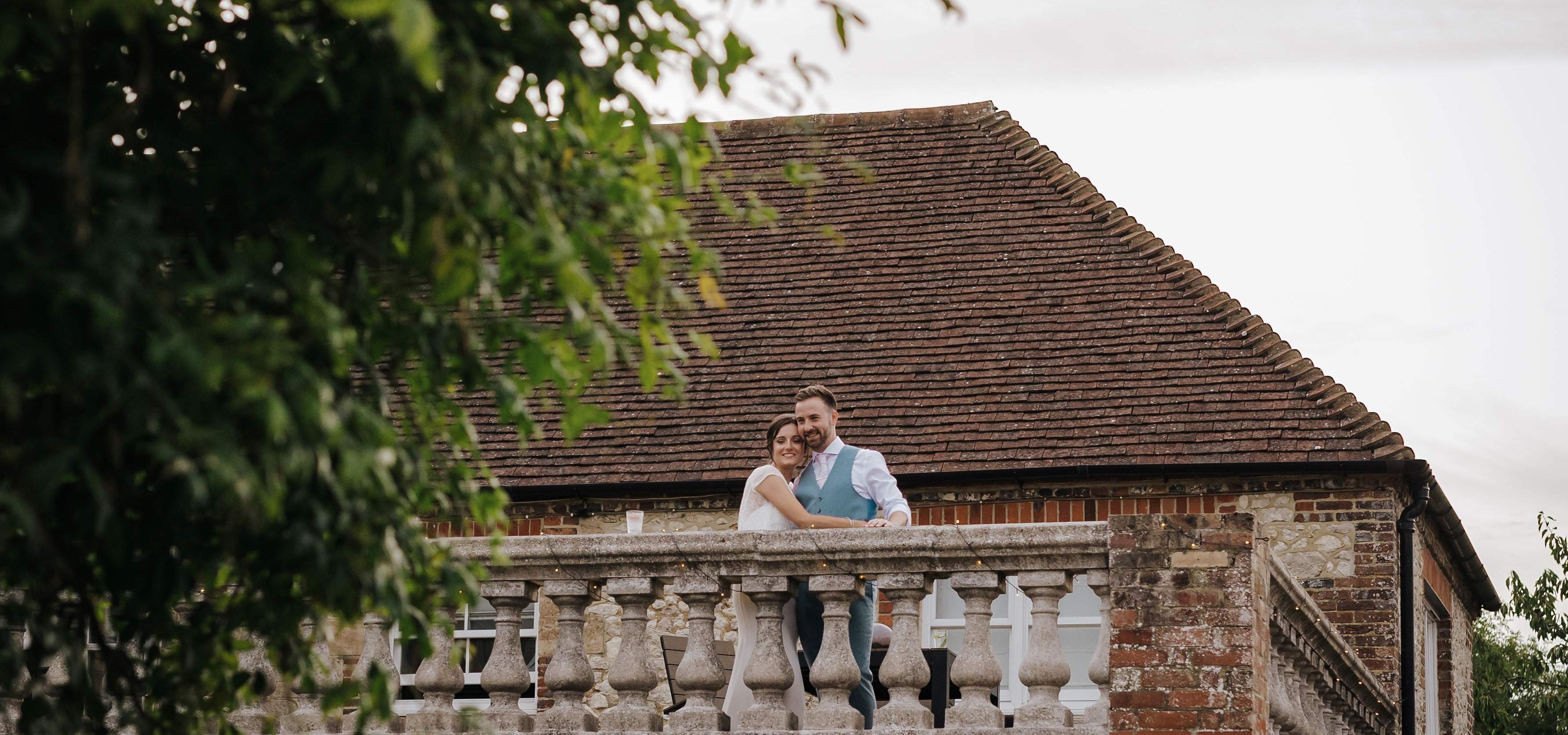 Bride and groom embracing on a stone balcony of a rustic country house