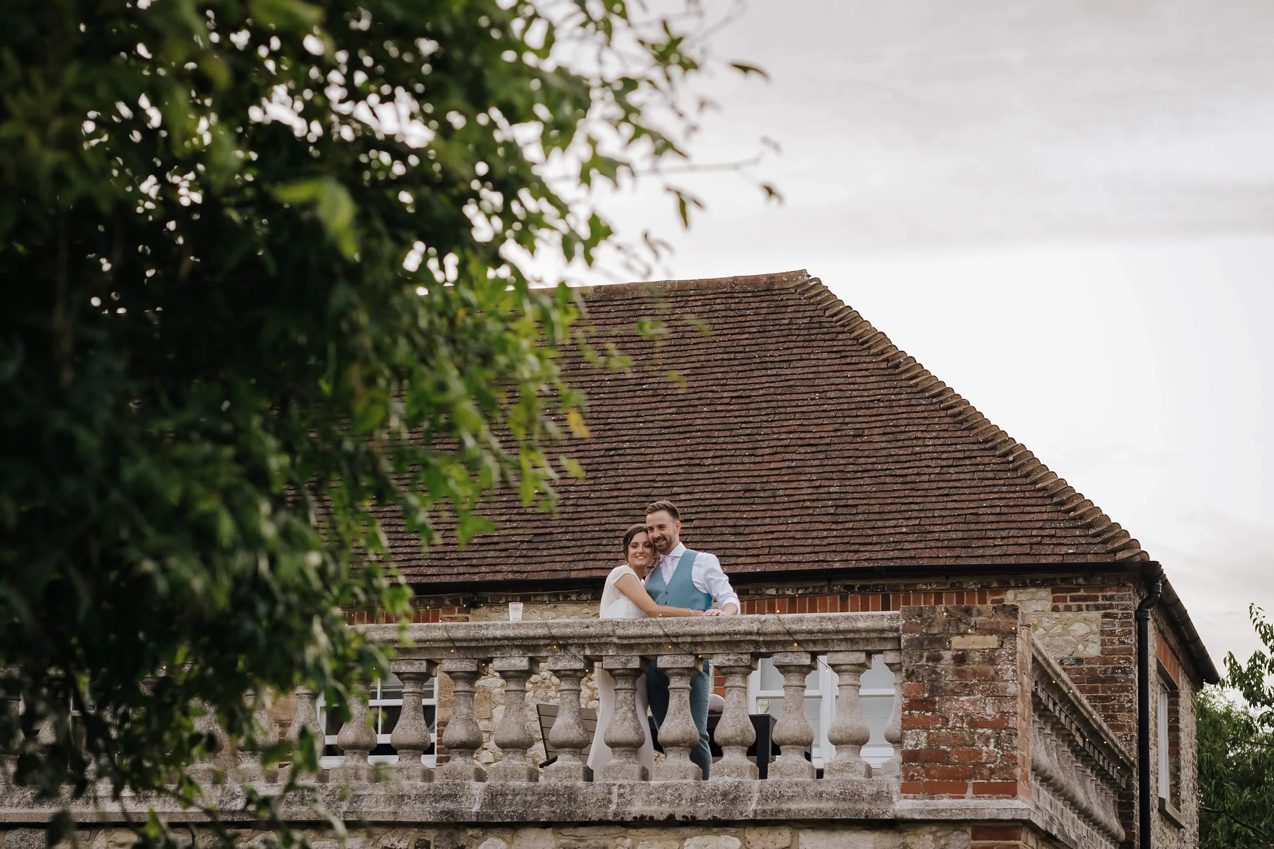 Bride and groom embracing on a stone balcony of a rustic country house