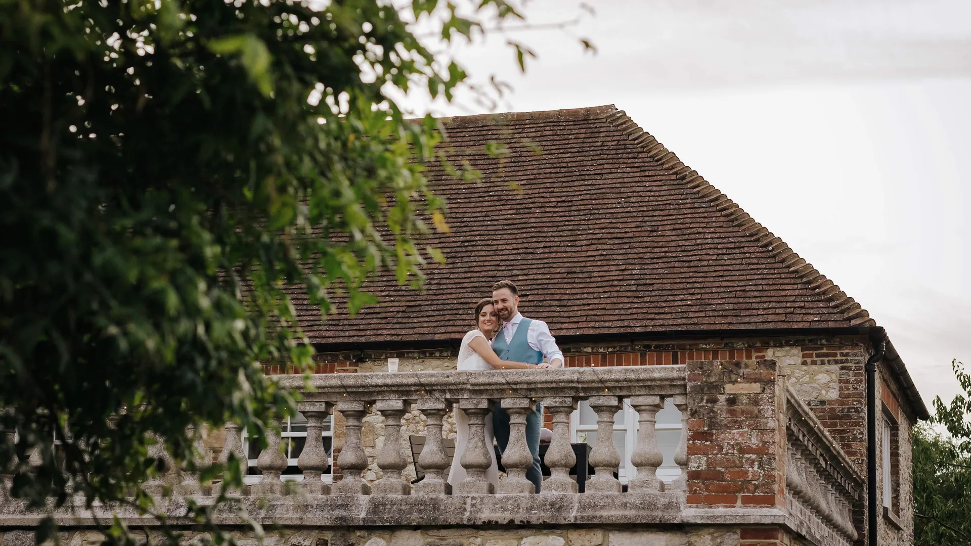 Bride and groom embracing on a stone balcony of a rustic country house