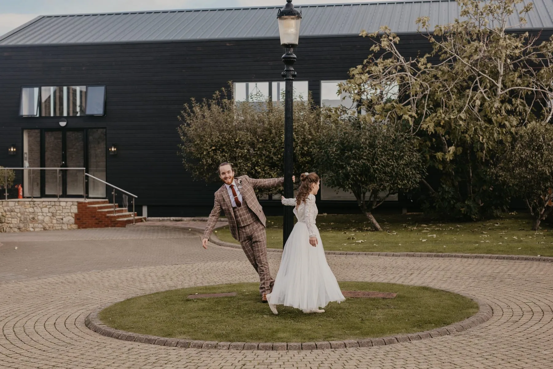 Bride and groom holding a lamppost outside a modern black building