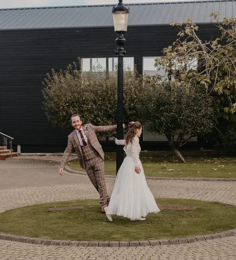 Bride and groom holding a lamppost outside a modern black building