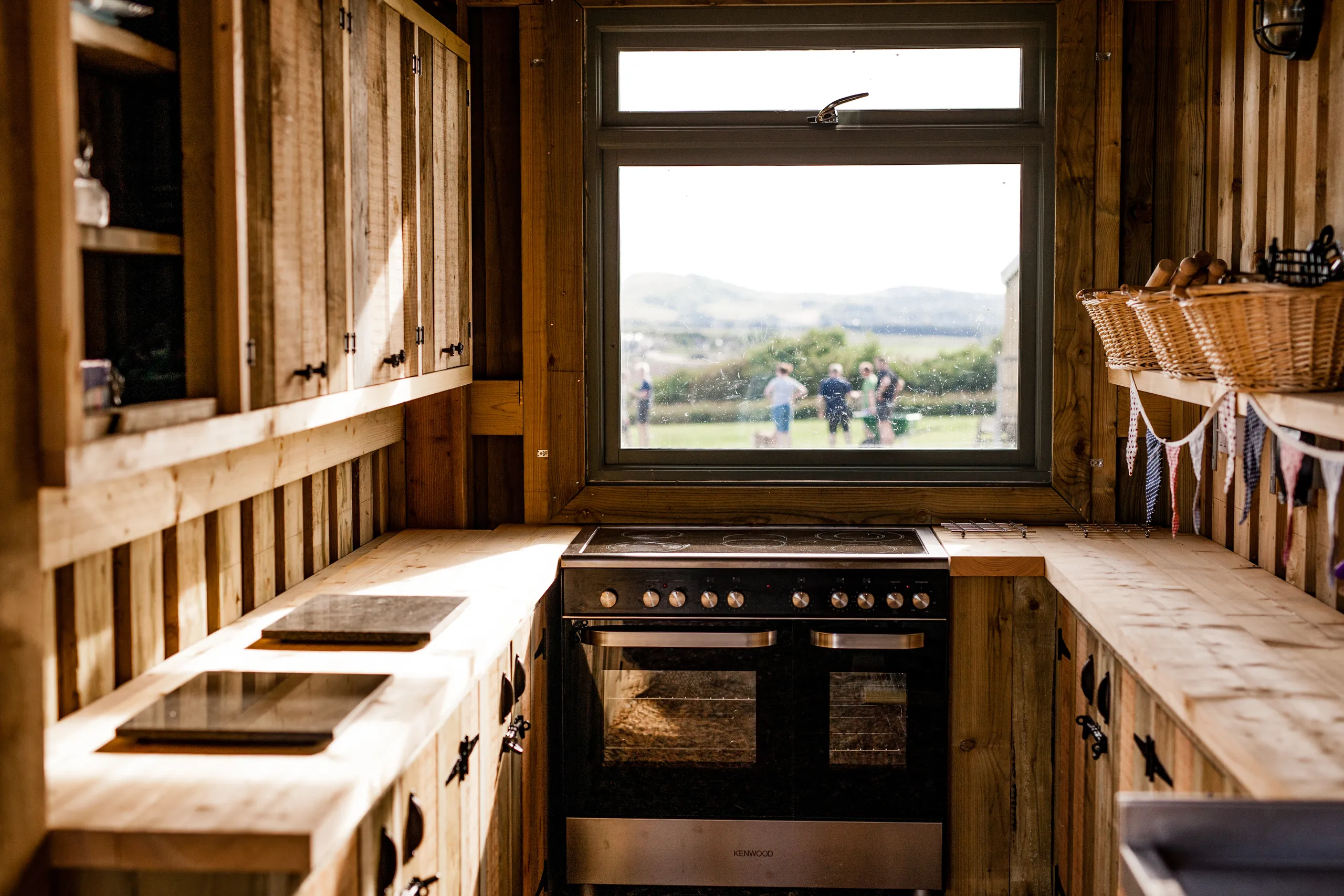 Rustic wooden cabin kitchen with double oven and window view over fields