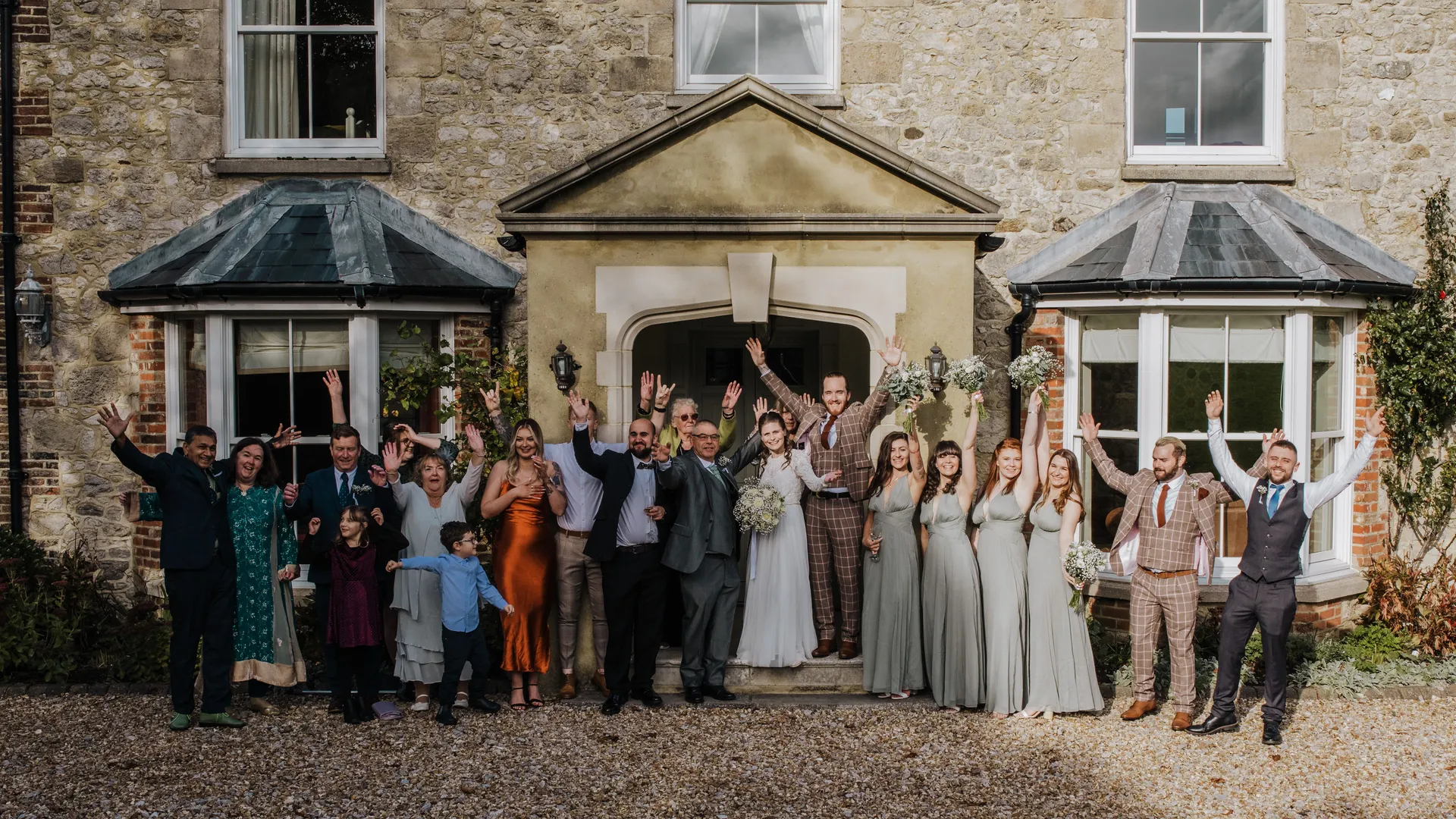 Wedding party cheering outside a stone house
