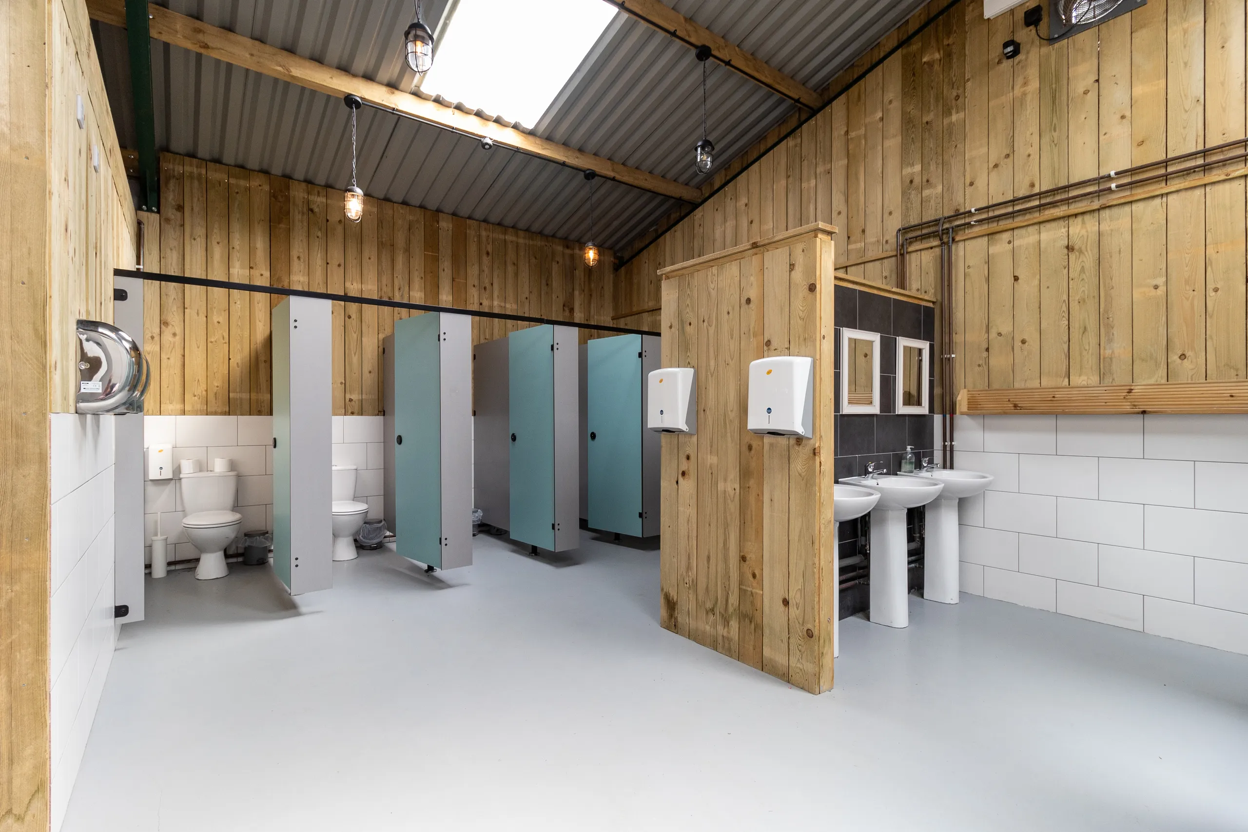 Modern campsite washroom with wooden walls, toilet cubicles and sinks