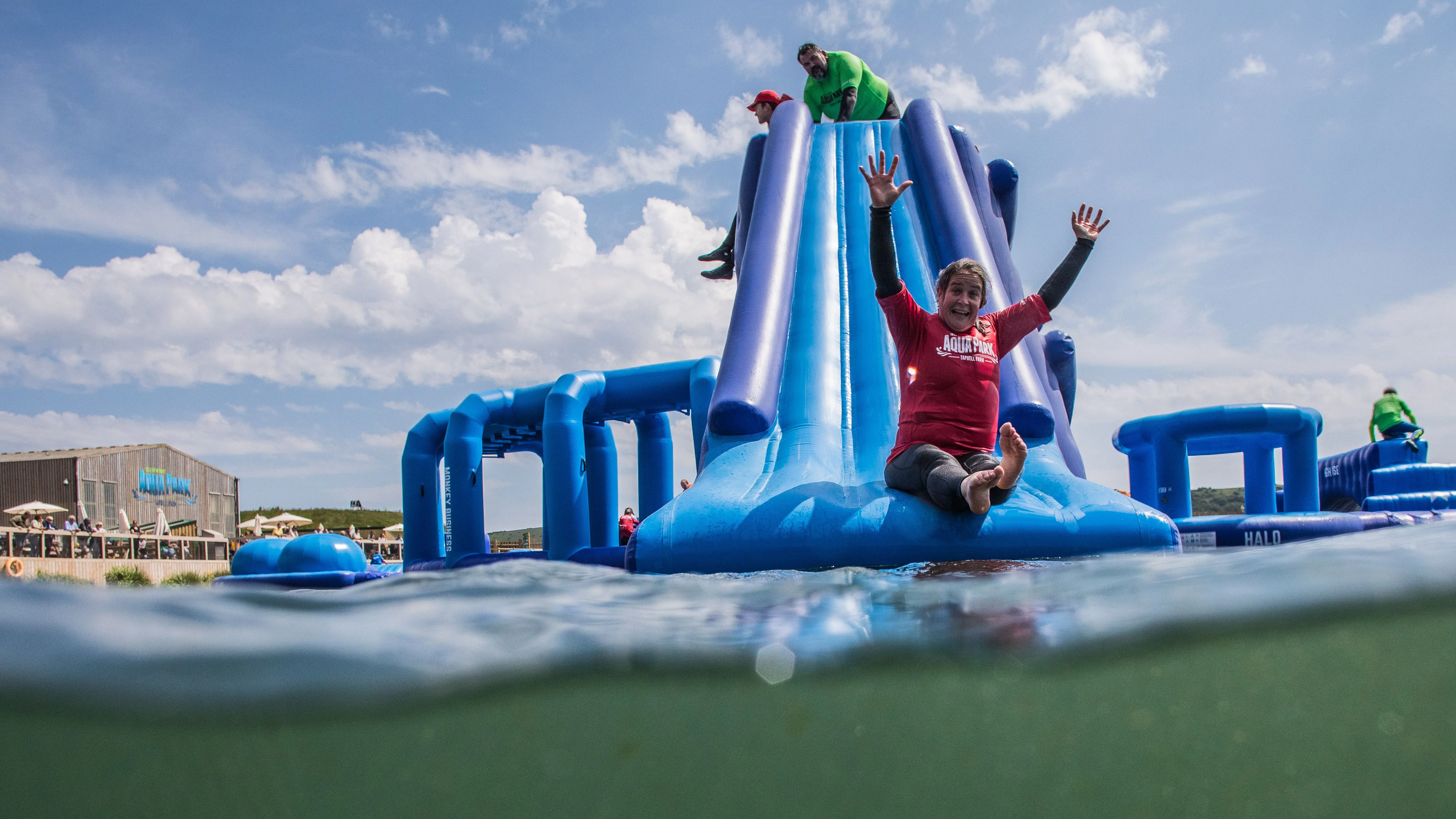 Person sliding down a large blue inflatable water slide at an outdoor aqua park