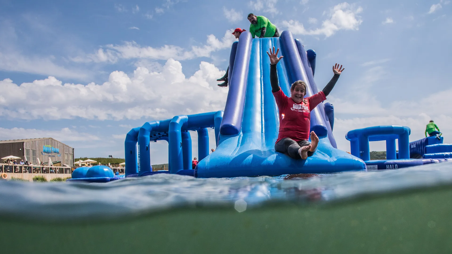 Person sliding down a large blue inflatable water slide at an outdoor aqua park