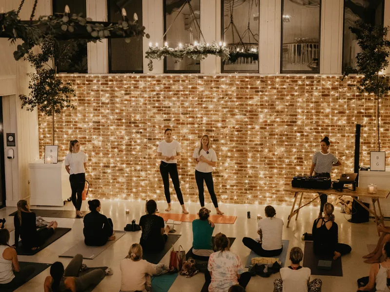 Yoga workshop in a cosy studio with fairy lights, instructors at the front and participants seated on mats