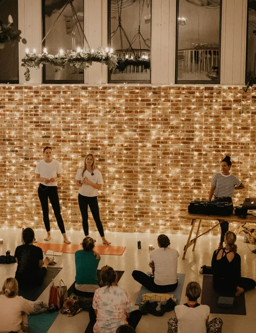 Yoga workshop in a cosy studio with fairy lights, instructors at the front and participants seated on mats