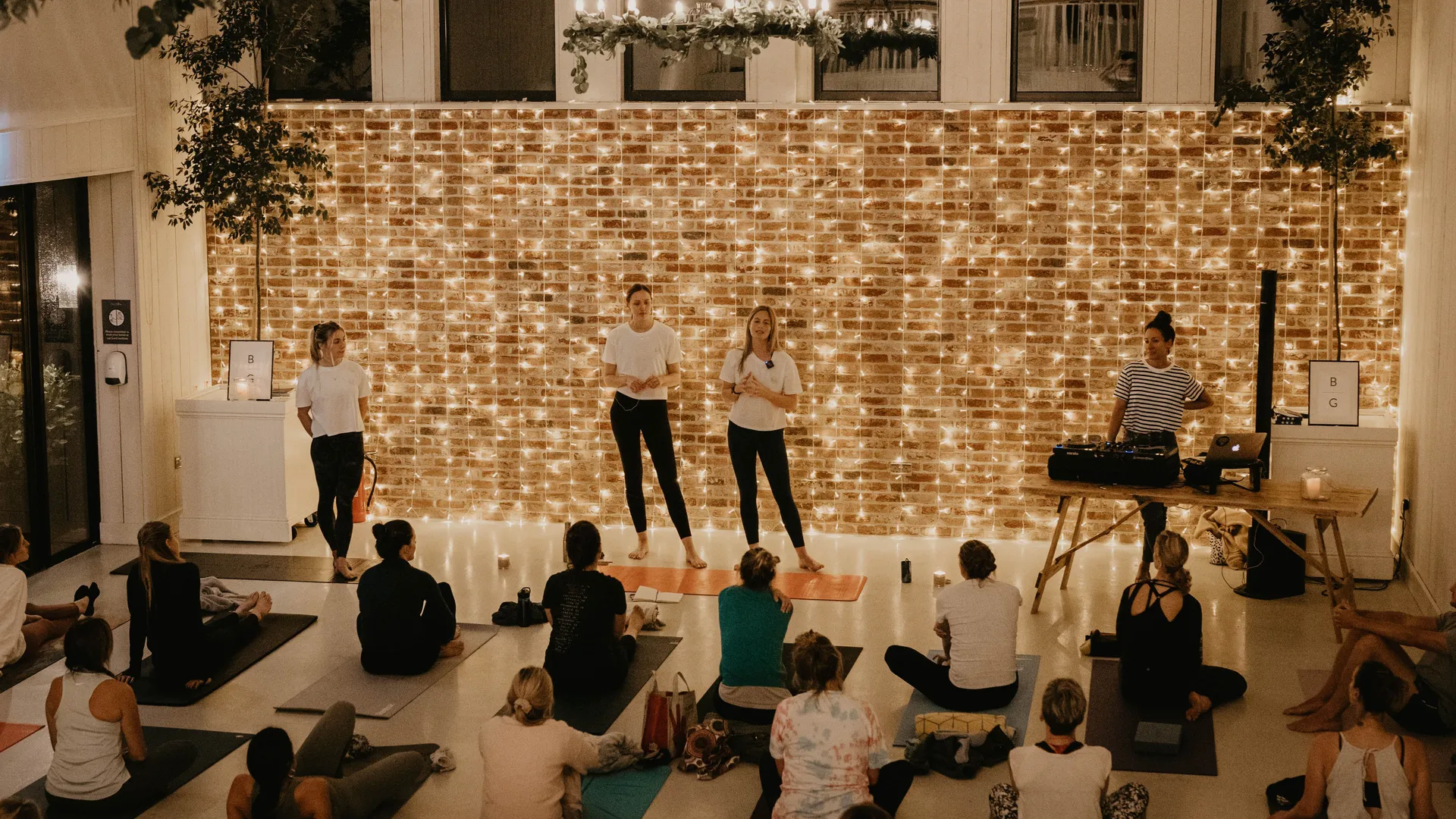 Yoga workshop in a cosy studio with fairy lights, instructors at the front and participants seated on mats