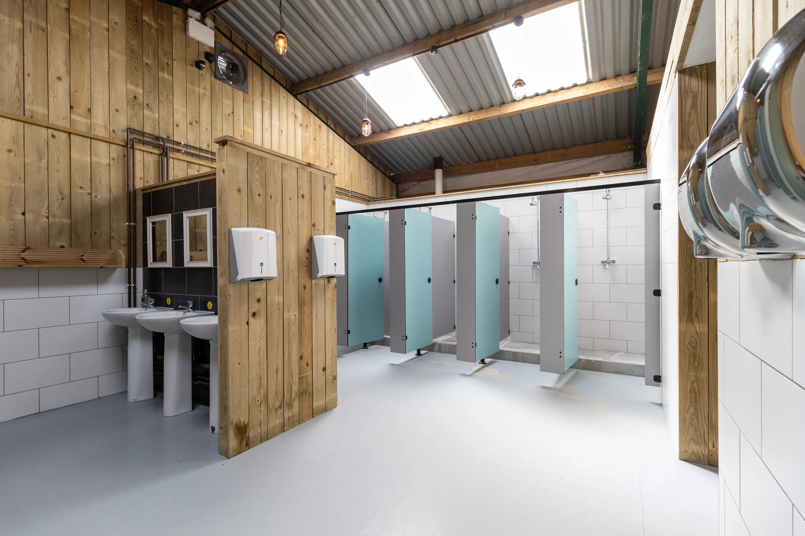 Clean campsite washroom with sinks, mirrors and shower cubicles in a timber-clad building