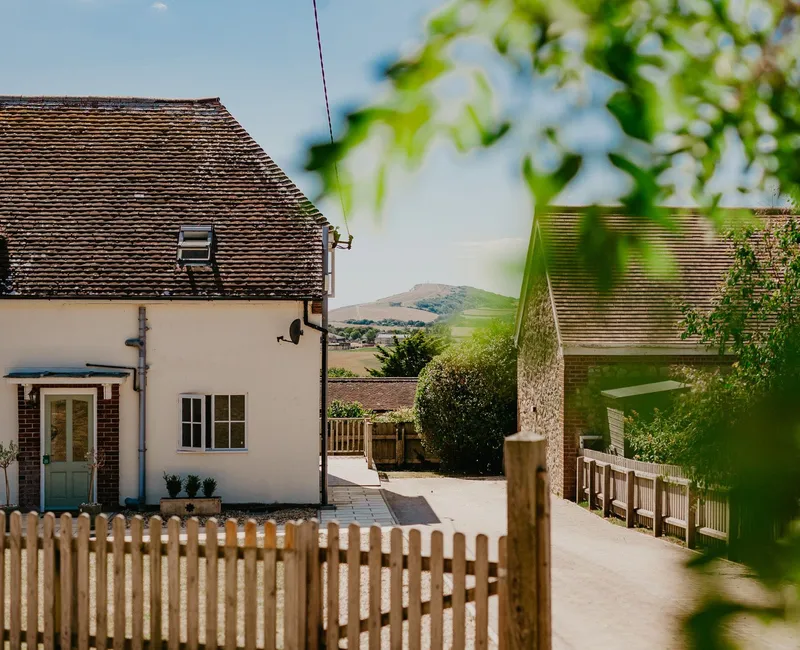 Country cottages with tiled roofs and picket fence, framed by green leaves